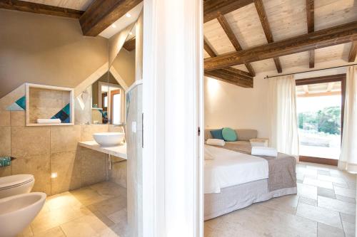 a bedroom with a bed and a bathroom with a sink at Villa Nicoletta in Santa Teresa Gallura