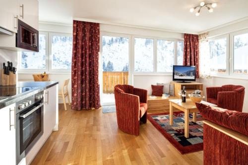 a kitchen and living room with red chairs and a table at Fewo-Obertauern Alps in Obertauern