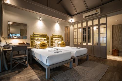 a bedroom with two beds and a desk and a mirror at Moracea by Khao Lak Resort in Khao Lak