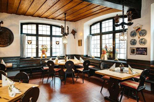 ein Restaurant mit Holztischen, Stühlen und Fenstern in der Unterkunft Brauereigasthof-Hotel Roter Ochsen in Ellwangen