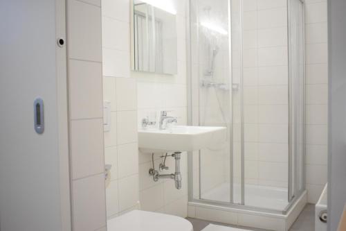 a white bathroom with a sink and a shower at SOVEA Hotel - City in Linz