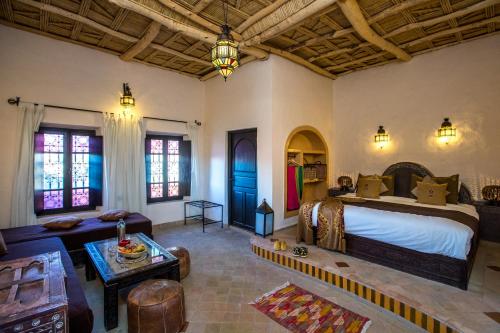 a bedroom with a large bed and a living room at Riad Madu in Merzouga