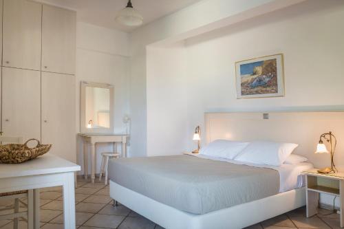 a white bedroom with a bed and a table at Panorama Apartments Fiscardo in Fiskardho