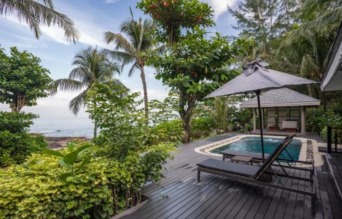 an outdoor deck with a pool and an umbrella at Moracea by Khao Lak Resort in Khao Lak