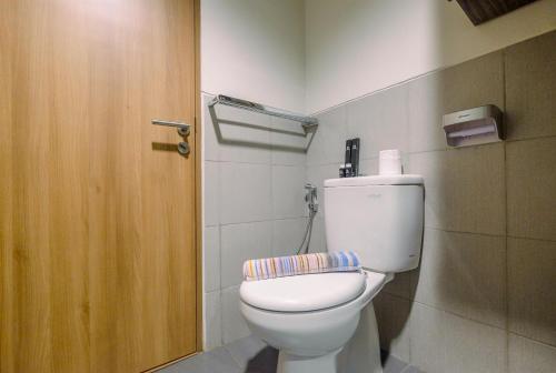 une salle de bain avec toilettes et porte en bois dans l'établissement Minimalist Studio at 11st Floor Bogor Icon Apartment By Travelio, à Kedunghalang