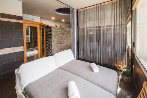 a white bed in a room with a large window at Hôtel Spa Restaurant La Madrague in Lucciana