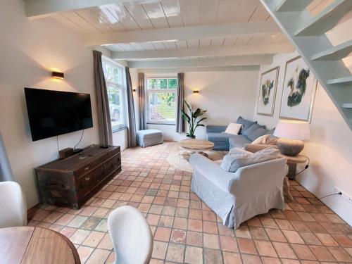 a living room with a couch and a tv at Cozy historical Cottage (Huisje HèHè) in Wassenaar