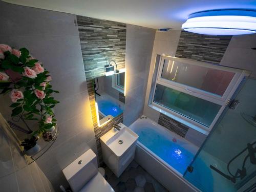 ein Bad mit einem WC, einem Waschbecken und einem Fenster in der Unterkunft Pass the Keys - 2BR Luxury Apartment with Jacuzzi Bath in Belfast