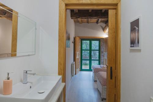 a bathroom with a sink and a living room at La Figal de Xugabolos, Salas in Salas
