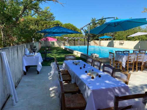 a restaurant with tables and umbrellas next to a pool at Hotel Carina in Apt