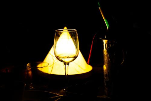 a candle in a wine glass next to a vase at Hôtel Restaurant Coco Lodge Majunga in Mahajanga