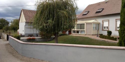 a white house with a tree in the yard at Gite Lammer in Artolsheim
