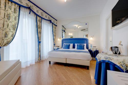 a bedroom with a blue and white bed and curtains at Hotel Cavalieri Palace & Suites in Lido di Jesolo