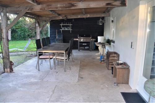 a patio with a wooden table and chairs at UNIEK Bommelgaard, guesthouse in het prachtige Rivierenland! in Hurwenen