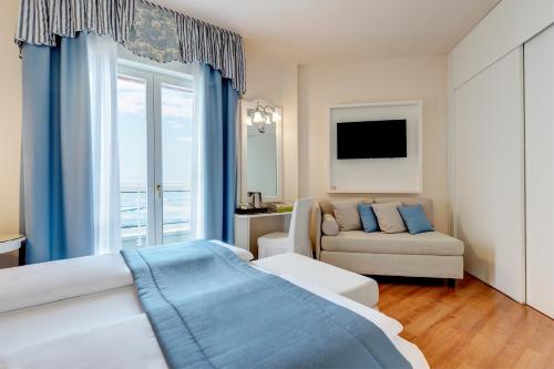 a living room with a couch and a tv in it at Hotel Cavalieri Palace & Suites in Lido di Jesolo