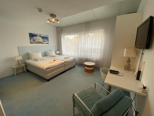een slaapkamer met een bed, een tv en een stoel bij De Slaapfabriek vakantiehuis en trainingslocatie in Teuge