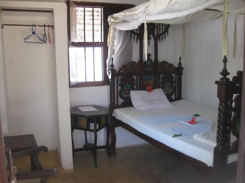 a bedroom with a bed and a table and windows at Jannat House in Lamu
