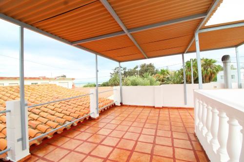 un patio extérieur avec du carrelage orange et un toit en bois dans l'établissement Global Properties, Adosado en la playa de Almardá, Sagunto, à Sagonte