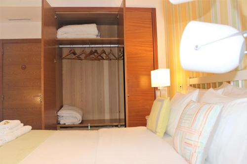 a bedroom with a white bed and a closet at Cosy Rooms in Sacavém