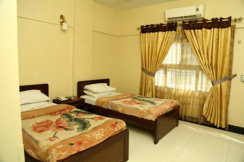カラチにあるHotel Bilalのベッドが2つと窓のある部屋