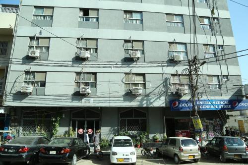 卡拉奇的住宿－比拉酒店，一座大型建筑,前面有汽车停放