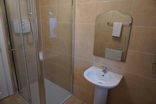 a bathroom with a shower and a sink and a glass shower stall at Lignaul Cottage in Donegal