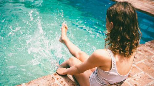 a woman sitting on the edge of a swimming pool at Posada Paradiso in José Ignacio