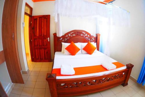 een slaapkamer met een houten bed met oranje en witte kussens bij M Luxury Apartments O2. in Mombasa