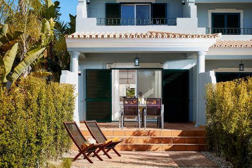 een huis met 2 stoelen op een patio bij Ancão Gardens in Quinta do Lago