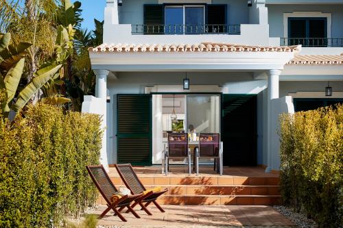 a house with two chairs on a patio at Ancão Gardens in Quinta do Lago
