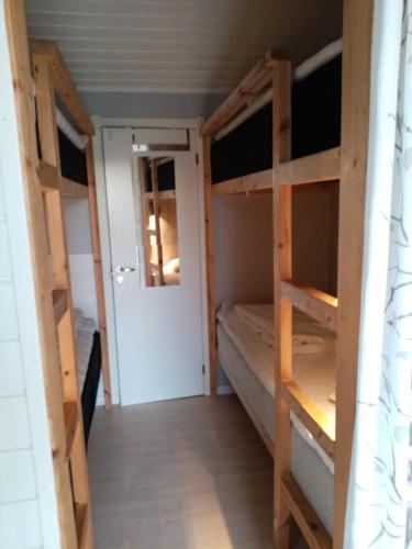 a room with two bunk beds and a door at Talluddens Stugby in Färjestaden