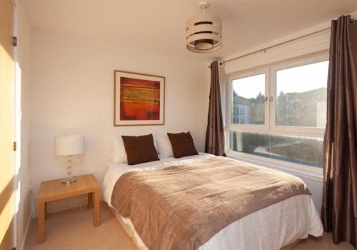 sypialnia z łóżkiem i dużym oknem w obiekcie The Lochend Park View Residence w Edynburgu