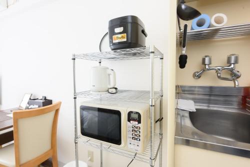 a microwave on a shelf next to a sink at COCOSTAY Global Noboricho4F ココステイ グローバル ノボリチョウ4F in Hiroshima
