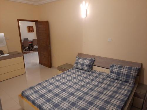um quarto com uma cama com lençóis xadrez azuis e brancos em Haut standing Appartement F5 meublé à Dakar Ngor virage em Dakar