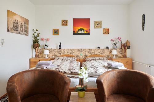two beds in a room with two chairs at Hüblers-Schlafquartier in Fürstenwalde