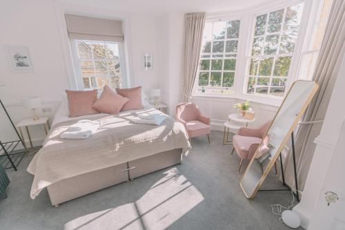 a bedroom with a bed and two chairs and windows at Old Bank Rooms in Bourton on the Water