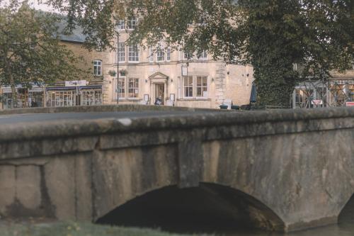 a stone bridge in front of a building at Old Bank Rooms in Bourton on the Water