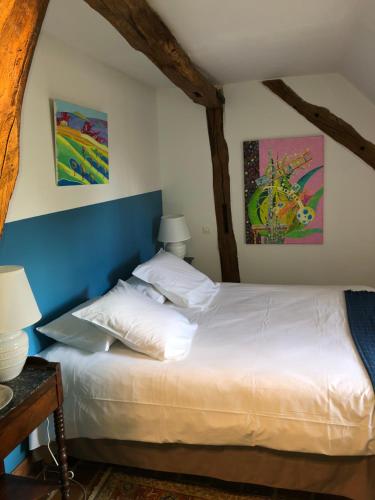 a bedroom with a bed and two paintings on the wall at Chambre d'hôtes Le Clos in Limeray