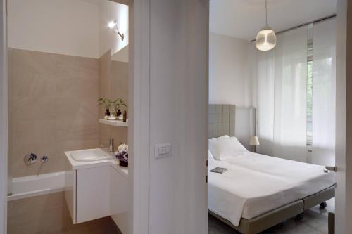 a white bedroom with a bed and a sink at Contempora Apartments - Elvezia 8 - E22 in Milan