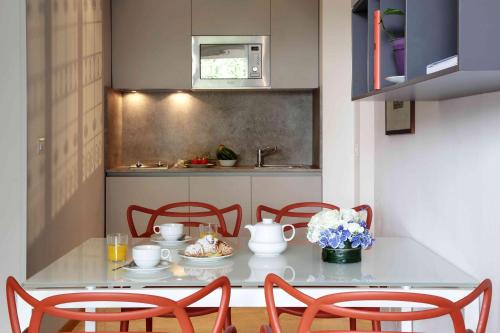 una cocina con una mesa con 2 sillas y una mesa con comida en Contempora Apartments - Elvezia 8 - E23, en Milán