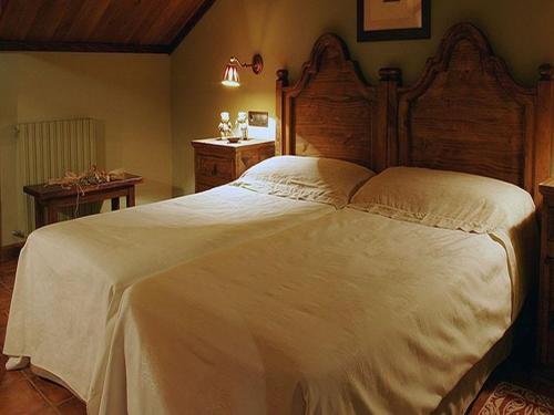 1 dormitorio con 1 cama blanca grande y cabecero de madera en Hotel Casbas, en Senegüé