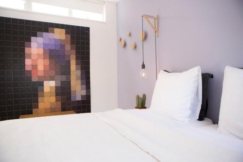 a bedroom with a white bed and a tile wall at B&B Achter de Kan in Den Bosch