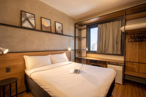 a hotel room with a bed with a book on it at ibis Ponta Grossa in Ponta Grossa