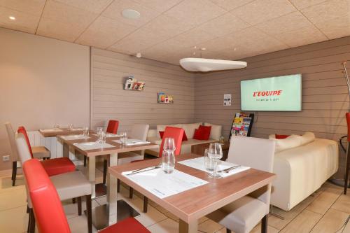 een restaurant met tafels en stoelen en een scherm bij Campanile Reims Sud - Bezannes in Reims