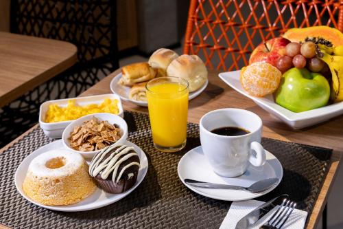 a table with plates of breakfast foods and a cup of coffee at ibis Ponta Grossa in Ponta Grossa
