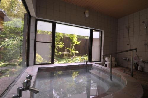 a bathroom with a tub with a large window at Tomomi Sanso / Vacation STAY 3832 in Yufuin