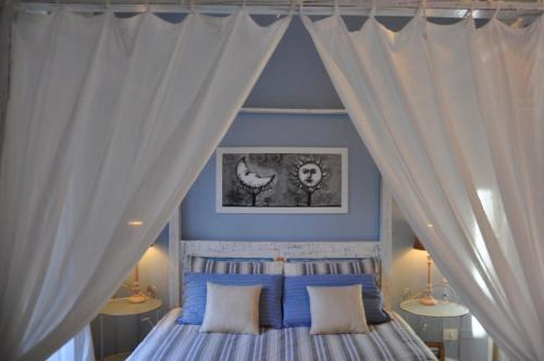a bedroom with a canopy bed with white curtains at New Romantic in Cagliari