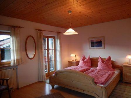 a bedroom with a large bed with pink pillows at Zaissererhof in Brannenburg