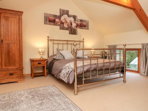 a bedroom with a bed and a wooden cabinet at Crooke Barn in Tiverton