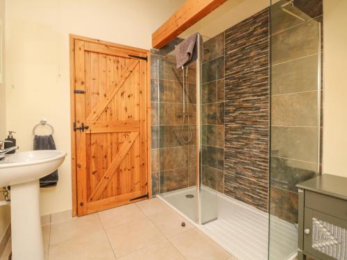 een badkamer met een douche en een glazen deur bij Crooke Barn in Tiverton